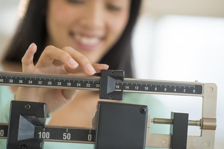 a woman weighing herself with a doctor's scale