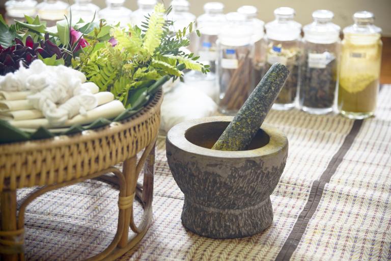 Ayurvedic herbal remedies in glass jars with a mortar and pestle.